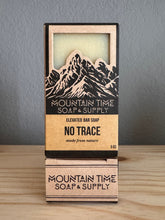 Bar of soap with packaging labeled 'Mountain Time Soap & Supply' on a wooden surface.
