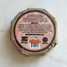 Round soap bar with compostable packaging and label on a light background