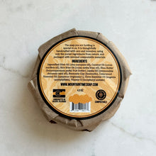 Round soap bar with compostable packaging on a marble surface